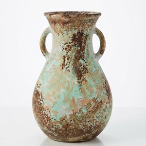 May include: A ceramic vase with a bulbous body and two side handles, featuring a mottled, textured finish in shades of brown, tan, and mint green. The surface displays a layered, painterly appearance with blended colors across the entire exterior.