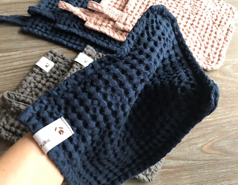 May include: A set of blue, gray, and pink waffle weave kitchen towels with a small brown label that says "The Little" on it.