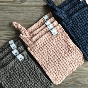 May include: Set of three waffle weave kitchen cloths in gray, pink, and blue. Each cloth has a loop for hanging and a small tag with the brand name.