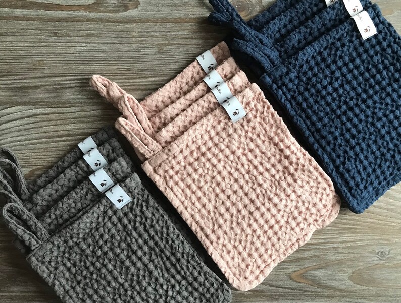 May include: Set of three waffle weave kitchen cloths in gray, pink, and blue. Each cloth has a loop for hanging and a small tag with the brand name.