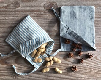 May include: Two small fabric bags with drawstrings. One bag is blue and white striped and contains peanuts. The other bag is solid blue and contains star anise.