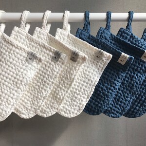 May include: Ten white and blue textured fabric pouches with loops hanging from a white rod. The pouches have a small white tag with the text "The Good" on them.