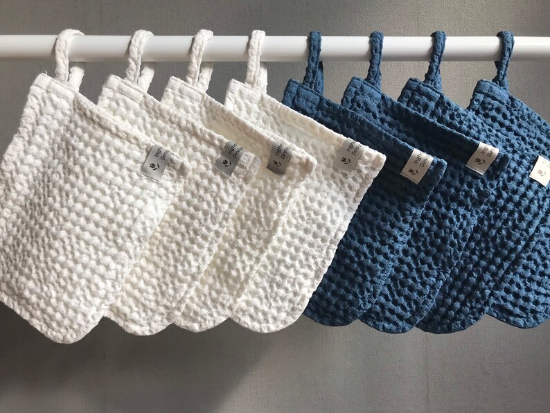 May include: Ten white and blue textured fabric pouches with loops hanging from a white rod. The pouches have a small white tag with the text "The Good" on them.