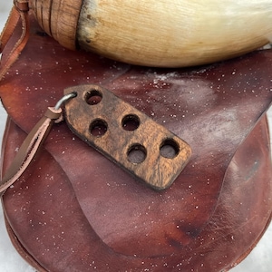 May include: A brown leather bag with a wooden toggle and a horn drinking vessel. The toggle has five holes in it.