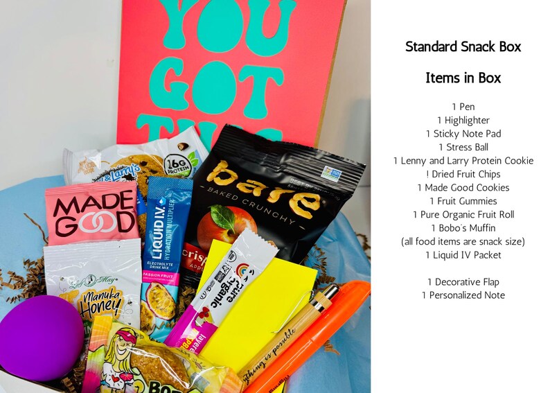 A gift box filled with snacks, a pen, highlighter, sticky note pad, and stress ball. The box includes a variety of packaged snacks, a purple stress ball, and a card with the words "YOU GOT THIS" in teal.