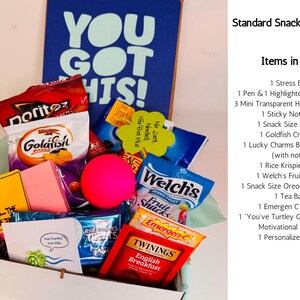 May include: A gift box filled with snacks and study supplies. Includes Doritos, Goldfish crackers, Welch's fruit snacks, a stress ball, highlighters, and a card that says "You Got This!" and "Studying - The Highlight of the Day".