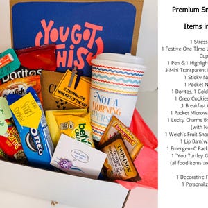 May include: A gift box filled with snacks, a coffee cup, and stationery. The box includes chips, cookies, crackers, and a stress ball. The blue background has the words "You Got This" in pink.