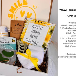 May include: A gift box filled with self-care items. Includes a ceramic mug, facial mask, socks, notebook, and a decorative sign that reads "Always be thankful for the little things." The box is decorated with yellow accents and sunflower details.