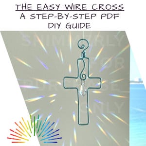 Op de afbeelding: Een turquoise draadkruis met een heldere kristallen hanger hangt tegen een witte achtergrond. De tekst "THE EASY WIRE CROSS A STEP-BY-STEP PDF DIY GUIDE" staat bovenaan. Het kruis is een doe-het-zelf knutselproject.