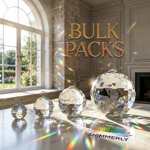 May include: Four clear, multi-faceted crystal spheres of varying sizes, each featuring a small metal hanging loop at the top. The text BULK PACKS is displayed in gold, and the word SHIMMERLY is printed below with a rainbow-colored sunburst icon.