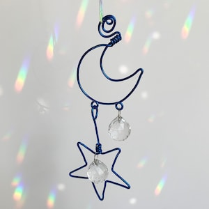 May include: A blue wire-wrapped moon and star mobile with crystal prisms hanging from each shape.