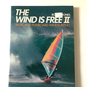 May include: A book titled "The Wind Is Free II" with the subtitle "Basic and Funboard Windsurfing." The cover shows a windsurfer on a wave. The title is in large white letters, with the author's name and a price tag visible.