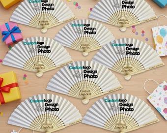 May include: Seven white folding hand fans arranged in a circular pattern, each featuring a black printed design with the text Custom logo Design Photo and Custom Logo/Text, surrounded by colorful gift boxes and patterned gift bags.