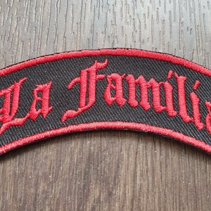 Peut inclure: Un patch brodé noir et rouge avec le texte "La Familia" dans une police gothique.