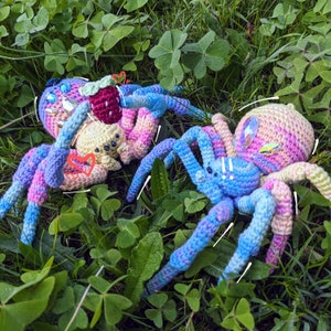 This photo shows two crochet spiders together. One is holding a small strawberry to give to the other.