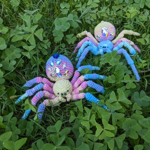 This photo shows two crocheted spiders in grass