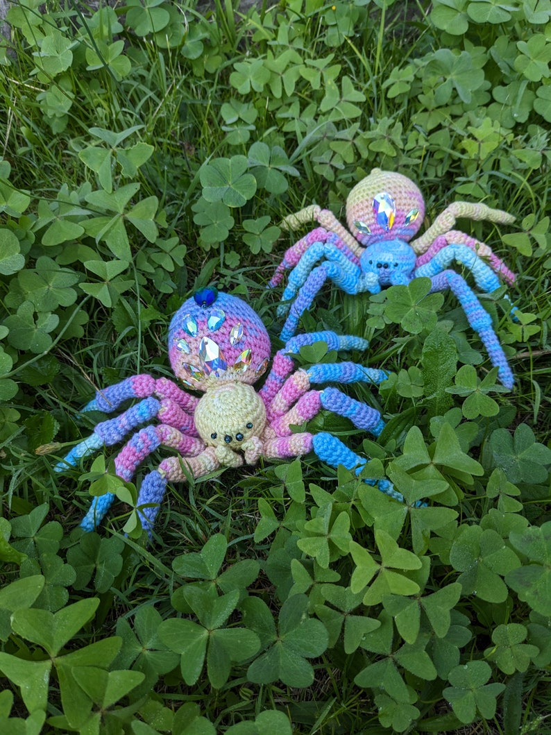 This photo shows two crocheted spiders in grass