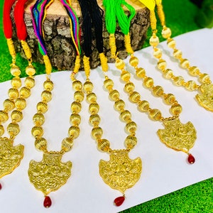 May include: Five gold necklaces with round beads and ornate pendants. Each pendant has a red stone at the bottom.