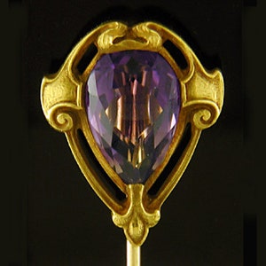 May include: A gold tie tack with an ornate design featuring a large, faceted amethyst gemstone.