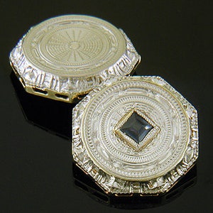 May include: A pair of gold cufflinks with intricate geometric designs. One cufflink features a small, dark blue gemstone in the center.