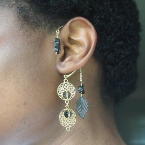 May include: Gold ear cuff with black beads and a leaf design. The ear cuff is worn on the upper part of the ear.