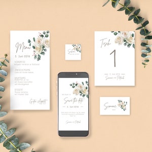 May include: Wedding stationery set with white roses and greenery. The set includes a menu, save the date card, table number card, and a place card. The text on the cards reads "Menu", "Save the Date", "Tisch 1", and "Simone".