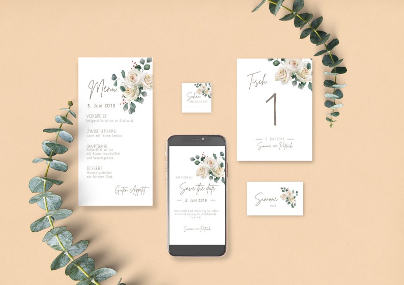 May include: Wedding stationery set with white roses and greenery. The set includes a menu, save the date card, table number card, and a place card. The text on the cards reads "Menu", "Save the Date", "Tisch 1", and "Simone".