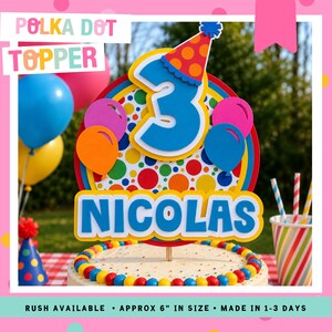 May include: A colorful polka dot cake topper with the word "NICOLAS" and the number "3". The topper includes balloons and a party hat. The topper is approximately 6 inches in size.