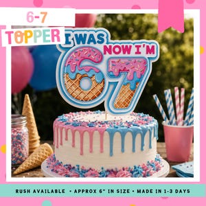 Puede incluir: Una tarta de cumpleaños con glaseado rosa y azul, coronada con un adorno de tarta decorativo "I WAS 67 NOW I'M". El adorno está diseñado para parecerse a un donut y un cono de helado. La tarta mide aproximadamente 15 cm.