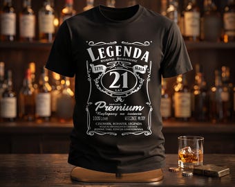 May include: A black short-sleeve t-shirt featuring white graphic text that reads LEGENDA, 21 LAT, Premium, and other phrases in a whiskey label style. The design includes decorative flourishes and borders centered on the front of the garment.