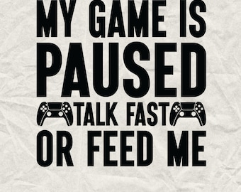 May include: Black and white graphic design with the text "My game is paused talk fast or feed me" and two stylized game controller icons.