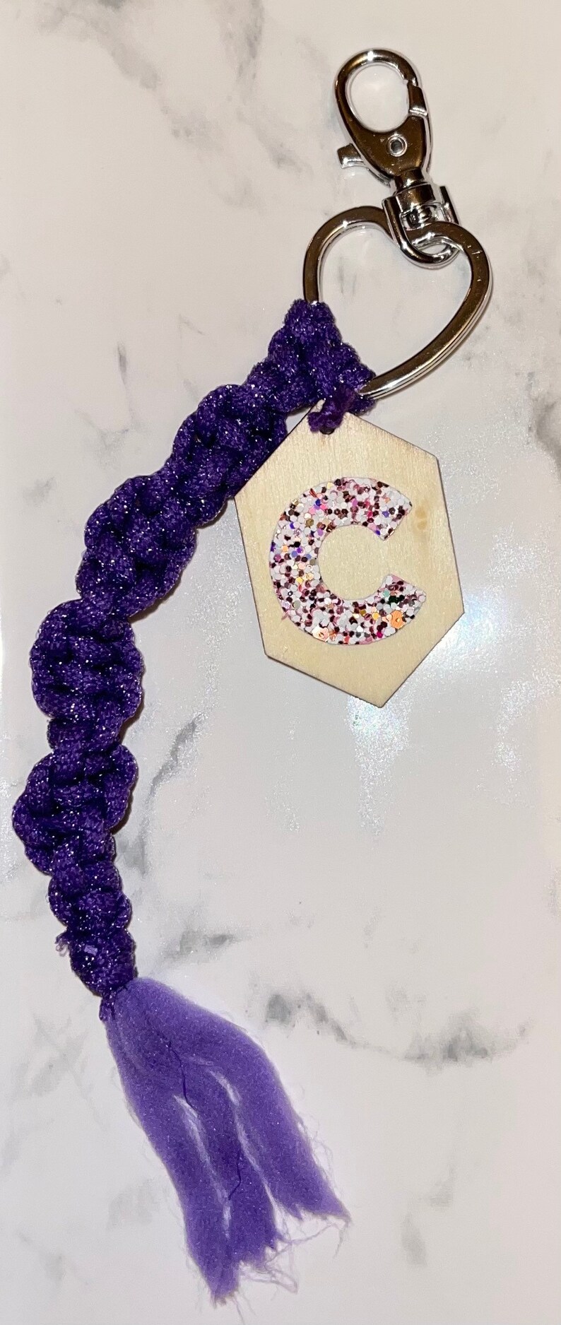 May include: Purple and silver keyring with a wooden hexagonal charm featuring a glitter letter C.