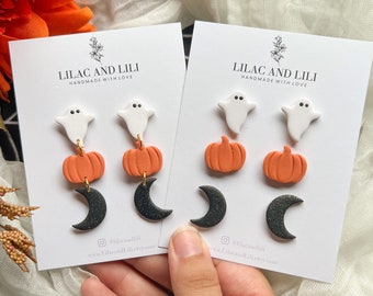 Può includere: Un set di tre paia di orecchini a tema Halloween. Gli orecchini presentano un fantasma bianco, una zucca arancione e una luna crescente nera. Gli orecchini sono fatti a mano e sono disponibili per l'acquisto su Etsy.