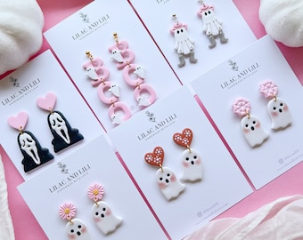 Può includere: Sei paia di orecchini fatti a mano in argilla polimerica con vari temi di Halloween. Gli orecchini includono fantasmi, cuori e le lettere "BOO" con accenti di fantasmi. Gli orecchini sono esposti su carte bianche con il testo "Lilac and Lili Handmade with Love".