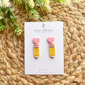 Pu&ograve; includere: Un paio di orecchini a forma di cuore rosa e matita gialla. Gli orecchini sono fatti a mano con amore da Lilac and Lili. Gli orecchini sono disponibili per l'acquisto su Etsy.