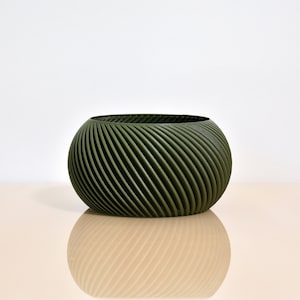 May include: A green ceramic planter with a swirling, textured design. The planter is round and has a wide opening.
