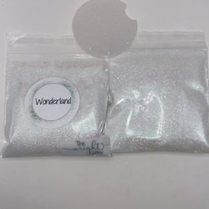 May include: Two small bags of white glitter with the text "Wonderland" on one bag and "The Wright Glitter" on the other.