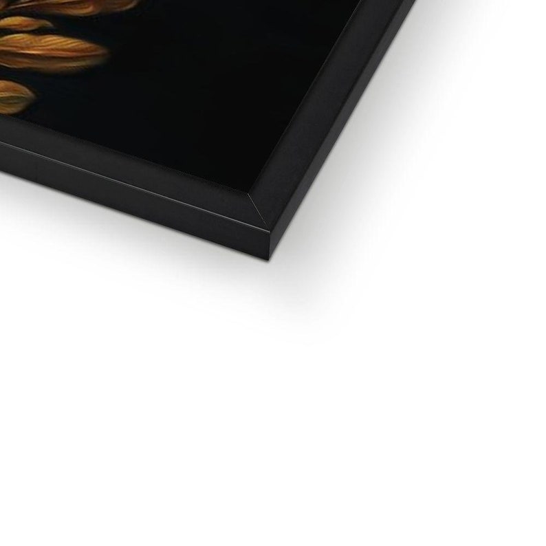 May include: A framed artwork with a close-up of golden-brown feathers on a black background. The artwork is in a black frame, creating a contrast. The image is angled, showing the corner of the frame.