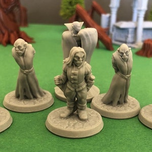 Puede incluir: Siete figuras en miniatura de plástico gris de vampiros, cada una de pie sobre una base redonda. Las figuras están vestidas con varios estilos de ropa, incluyendo capas y trajes. Las figuras están dispuestas en semicírculo sobre una superficie verde.