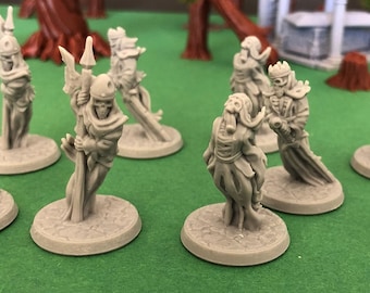 Puede incluir: Un conjunto de nueve figuras en miniatura de plástico gris que representan esqueletos vestidos con túnicas y sosteniendo lanzas. Las figuras están de pie sobre bases redondas.