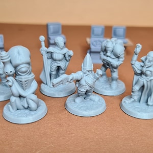 Könnte beinhalten: Ein Set aus sieben grauen bemalten Miniaturfiguren, darunter ein Ritter, ein Zauberer, ein Zwerg, eine Kreatur mit Tentakeln und drei weitere Figuren. Die Figuren stehen auf runden Sockeln.