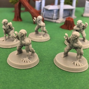 Pode incluir: Seis figuras em miniatura de plástico cinza de zumbis com mãos com garras e dentes longos e afiados. As figuras estão em uma variedade de poses dinâmicas e estão em pé sobre bases redondas cinzas.