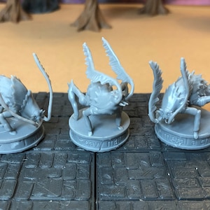 May include: Three grey plastic miniature figures of a creature with multiple legs and spiky appendages. The figures are standing on round bases with text that reads "heavy metal", "metal a che", and "heavy metal".