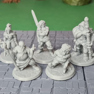 Könnte beinhalten: Fünf graue Plastik-Miniaturfiguren von Fantasy-Charakteren, die jeweils auf einem runden Sockel stehen. Die Figuren umfassen einen Krieger mit einem Schwert, einen Zauberer mit einem Stab, einen Kleriker mit einem Stab, einen Schurken mit einem Dolch und einen Waldläufer mit Bogen und Pfeil.