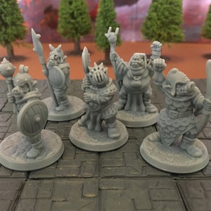 Op de afbeelding: Vijf grijze plastic miniatuurfiguurtjes van orcs, elk met een ander wapen en pose. De orcs staan op een grijs en zwart betegeld oppervlak.