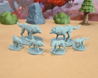 Può includere: Una collezione di figurine di lupi grigi in varie pose, tra cui in piedi e in cammino. Le figurine sono su piccole basi rotonde e sono probabilmente per giochi da tavolo o esposizioni. La scena include elementi di terreno in miniatura.