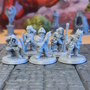 May include: Five grey miniature fantasy figurines, including an archer, a knight with a mace, and a warrior with a staff. The figures are on round bases and are set on a grey, tiled surface. Background elements include miniature trees and statues.