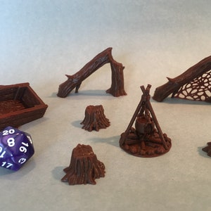 May include: A set of brown 3D printed miniature forest scenery pieces, including a fallen log, a log with a web, a campfire, and four tree stumps. A purple 20-sided die is also included.