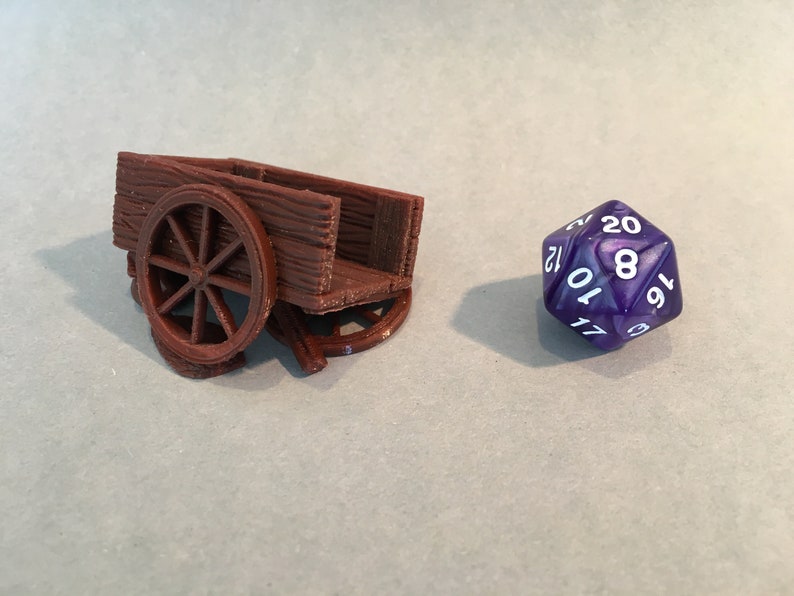 May include: A brown wooden miniature wagon with a single wheel. The wagon is sitting on a white surface next to a purple 20-sided die with white numbers.