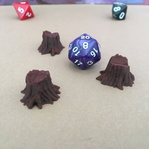 May include: Three brown tree stump miniatures and a purple 20-sided die with white numbers. The die is rolled and resting on the table.